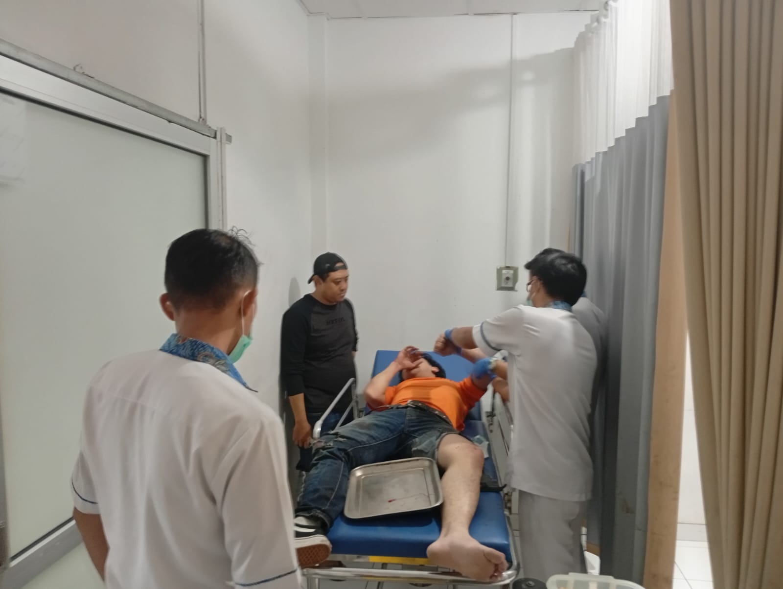 DIOBATI : Seorang pria yang melompat-lompati atap rumah warga pada Kamis pagi (14/8) saat diobati petugas rumah sakit.